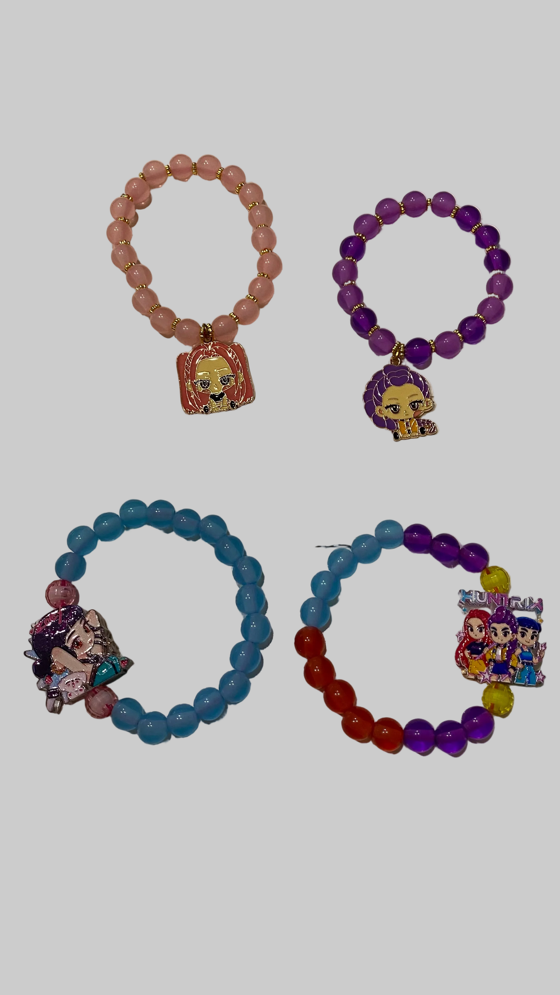 Four colorful beaded bracelets with character charms on a white surface